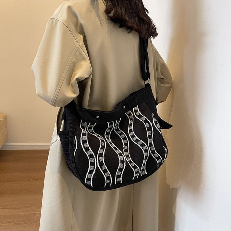 Umhängetasche mit gedrehtem Muster, breiter Riemen und magnetischer Schnalle